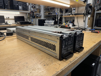 APC APCRBC140 replacement battery module on a wooden workbench, full length of the vented galvanised module — AI-generated image