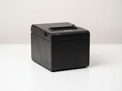 Epson OmniLink TM-m30II cube receipt printer in black, front three-quarter view on a white desk — AI-generated image