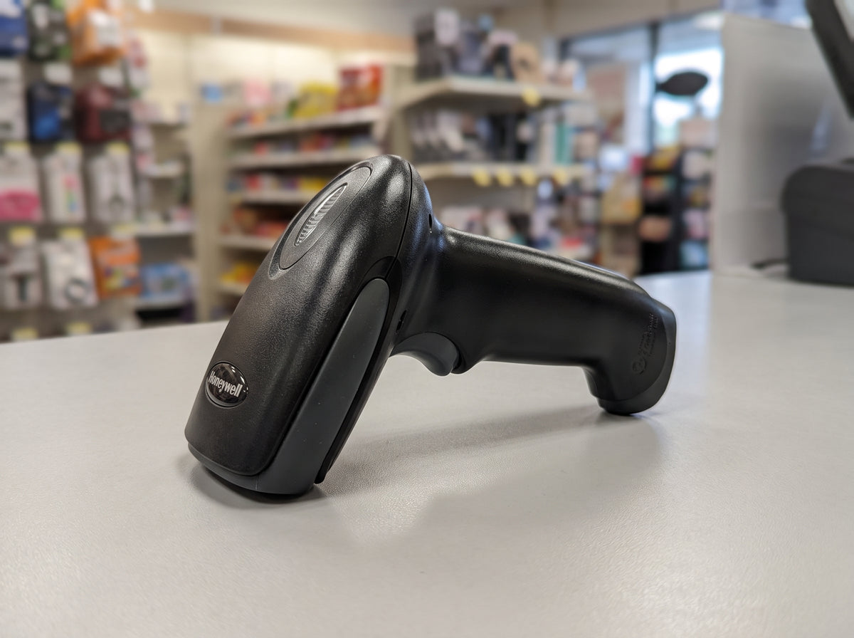 Honeywell Hyperion 1300g corded 1D linear imaging barcode scanner in black on a retail checkout counter — AI-generated image