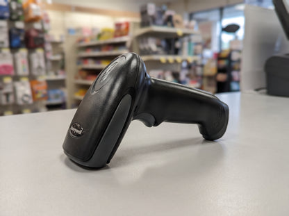 Honeywell Hyperion 1300g corded 1D linear imaging barcode scanner in black on a retail checkout counter — AI-generated image