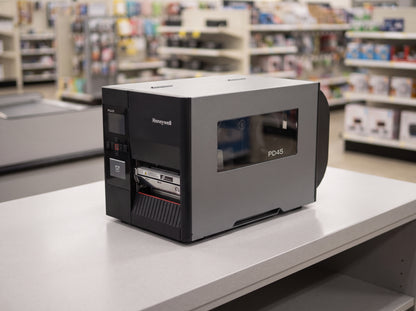 Honeywell PD45S industrial thermal transfer label printer in dark grey on a retail checkout counter — AI-generated image