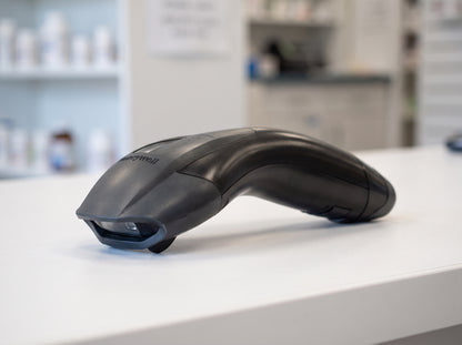 Honeywell Voyager 1200g corded 1D laser barcode scanner in black on a cafe counter — AI-generated image