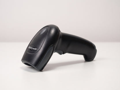 Honeywell Voyager 1200g corded 1D laser barcode scanner in black on a cafe counter — AI-generated image
