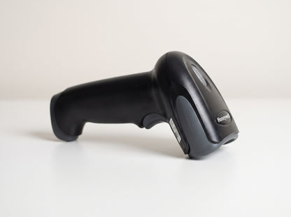 Honeywell Voyager 1250g corded 1D laser barcode scanner in black on a retail checkout counter — AI-generated image