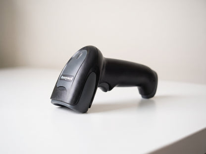 Honeywell Voyager 1250g corded 1D laser barcode scanner in black on a retail checkout counter — AI-generated image