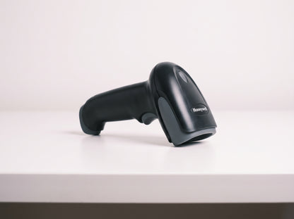 Honeywell Voyager XP 1470g corded 2D area imager barcode scanner in black on a retail checkout counter — AI-generated image