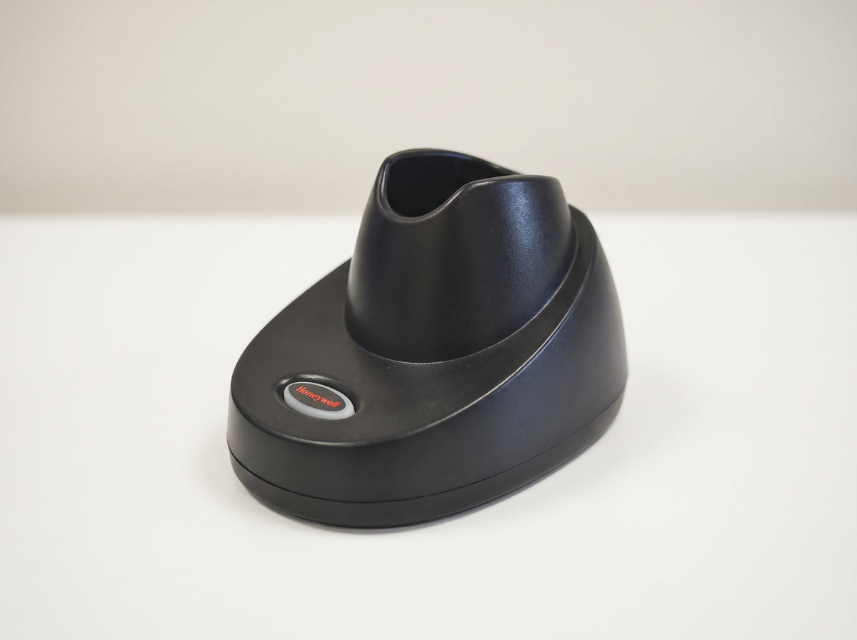 Honeywell CCB10 charging and communication base in black, shown empty on a retail checkout counter — AI-generated image