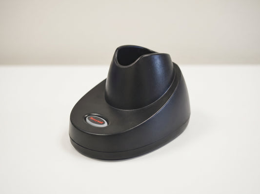 Honeywell CCB10 charging and communication base in black, shown empty on a retail checkout counter — AI-generated image