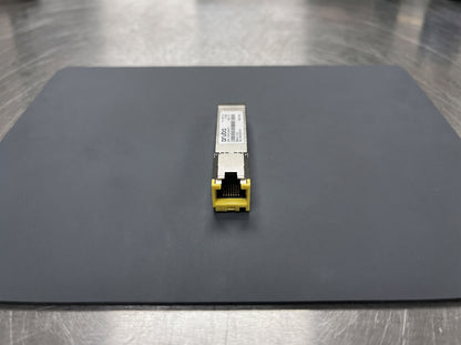 HPE Aruba 10GBASE-T SFP+ transceiver on an antistatic mat, RJ45 port toward the camera  — AI-generated image